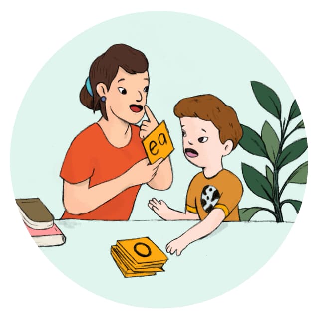 A speech therapist and young child using alphabet flash cards.