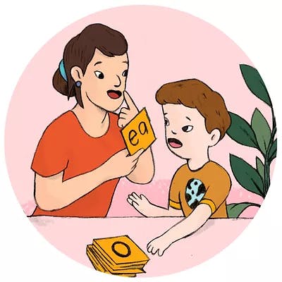 A speech therapist and young child using alphabet flash cards.