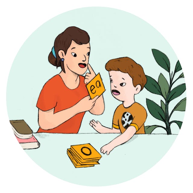 A speech therapist and young child using alphabet flash cards.